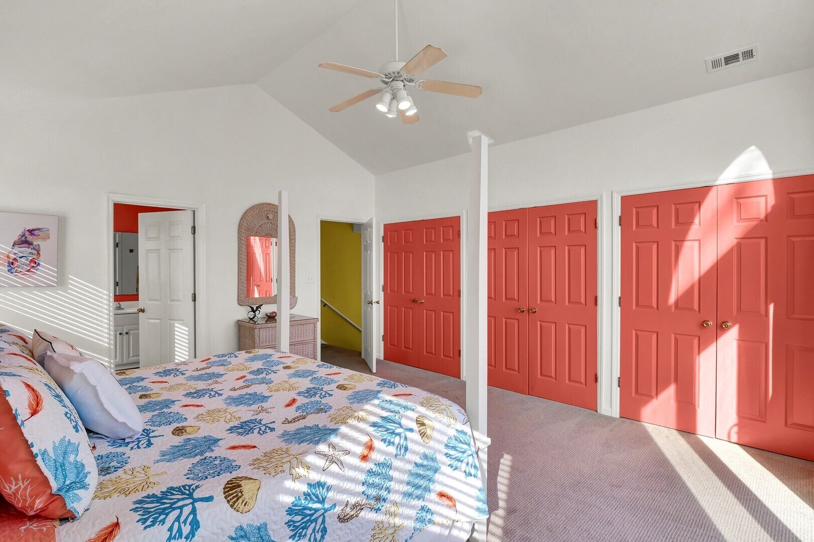 Un dormitorio con una cama, un ventilador de techo y dos puertas rojas.