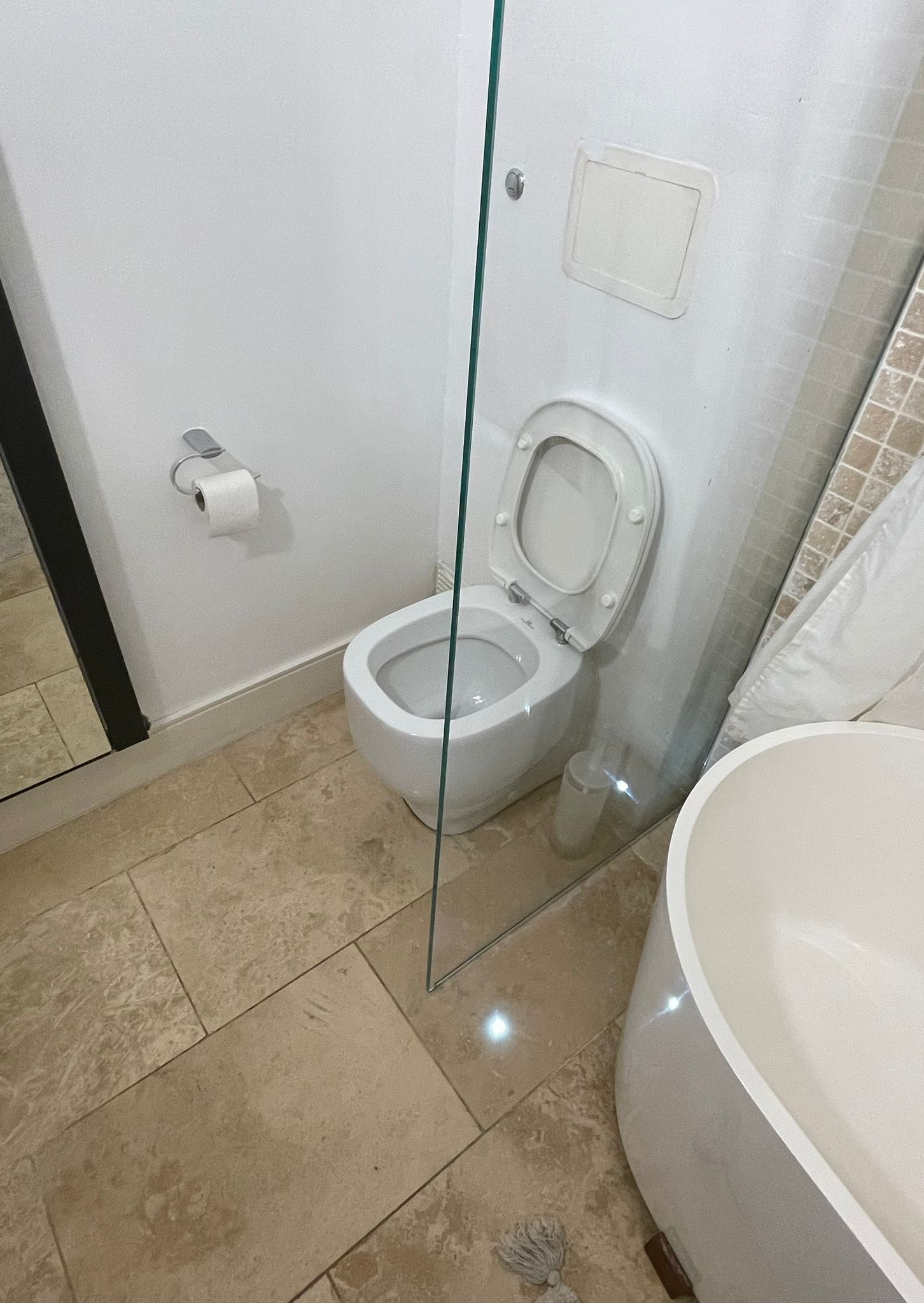 Een badkamer met toilet, glazen douchecabine en bad.