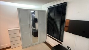 A room with a wardrobe, a bench, a radiator, and a window with blinds. - Lovely 2-bed Apartment in Brixton Central Location (London)