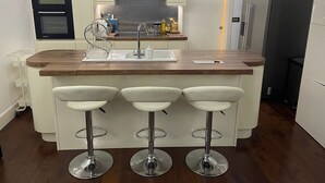 A modern kitchen with a central island, bar stools, a built-in oven, and a refrigerator. - Lovely 2-bed Apartment in Brixton Central Location (London)