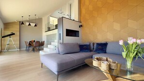 A modern living room with a grey sofa, a glass coffee table, and a telescope in the corner. - Penthouse Horizonte with stunning views in Colina del Sol (Cap Blanc Cullera)