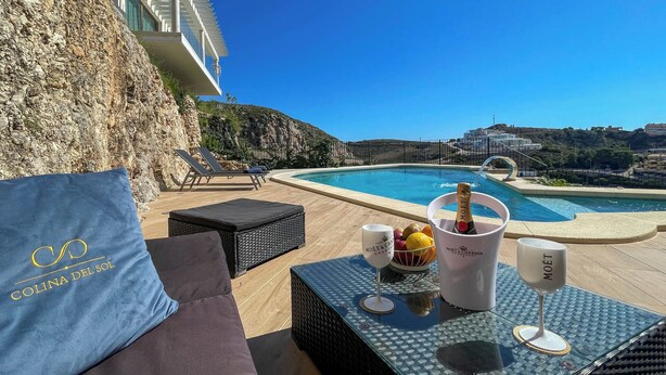 A poolside area with a view of the sea, a bottle of Moët champagne, and a table with a fruit bowl and glasses. - Penthouse Horizonte with stunning views in Colina del Sol (Cap Blanc Cullera)