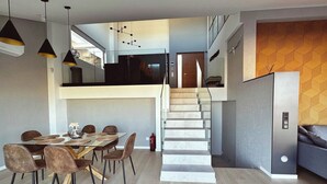 A modern interior with a dining area, staircase, and a living space. - Penthouse Horizonte with stunning views in Colina del Sol (Cap Blanc Cullera)