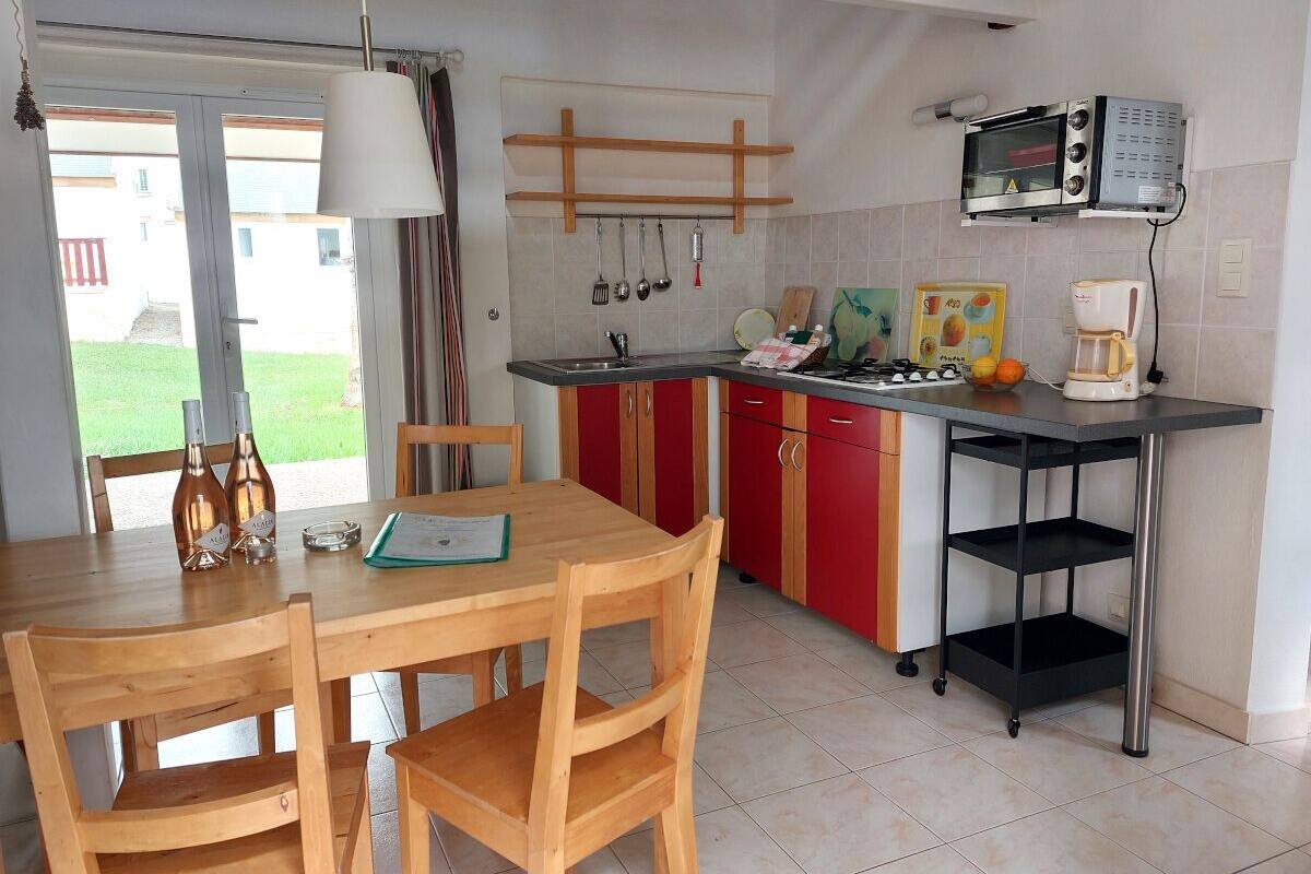 Una cocina con mesa, sillas, microondas y cafetera.