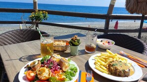 Una tavola apparecchiata con cibo, bevande e vista sulla spiaggia.