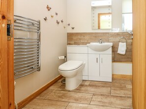 A modern bathroom with a toilet, sink, and mirror. There are butterfly decals on the wall and a towel hanging on the sink. - Dale View (Bishop Auckland)