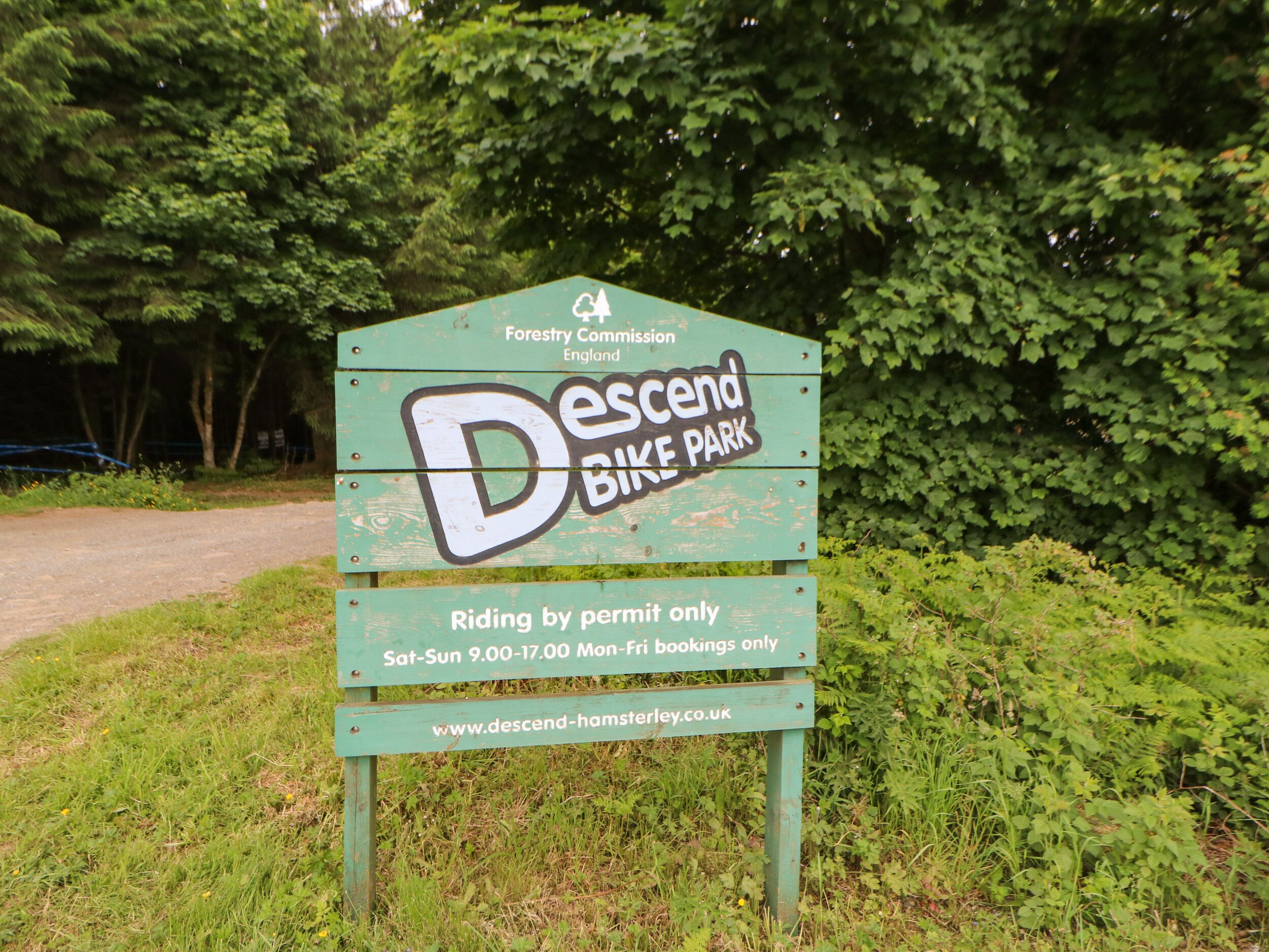 A sign for 'Descent Bike Park' with information about riding by permit and booking times.