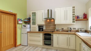 Una cocina compacta con armarios de madera, horno empotrado, cafetera y microondas.