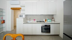 Une cuisine moderne avec des meubles blancs, un four à micro-ondes encastré, une cuisinière à gaz et un lave-vaisselle.