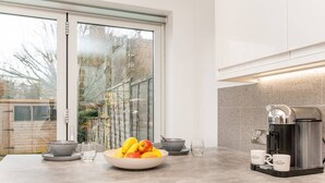 Una cocina moderna con un ventanal grande, una cafetera y un cuenco de fruta en la encimera.