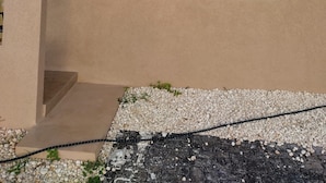 En bygning med beige facade, postkasse, gadelampe og et vindue med skodder.