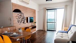 A modern living room with a dining area, a sofa, and a TV mounted on the wall. - Mondial Apartments By BnbHost (Salvador)