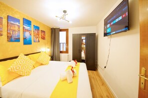 A hotel room with a bed, a TV mounted on the wall, and artwork on the wall.
