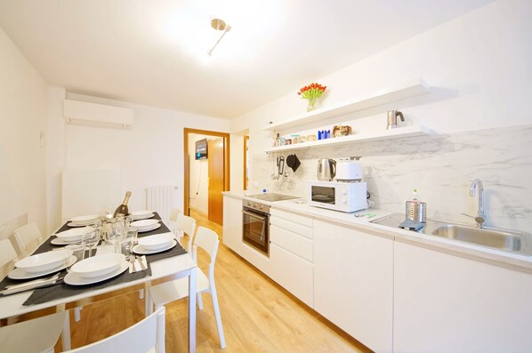 A modern kitchen with white cabinetry, a marble backsplash, and a built-in oven.