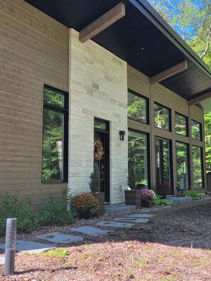 A modern building with large windows, a stone facade, and a covered entrance. - EARTH chalet in harmony with nature, Tremblant (Mont-Tremblant)