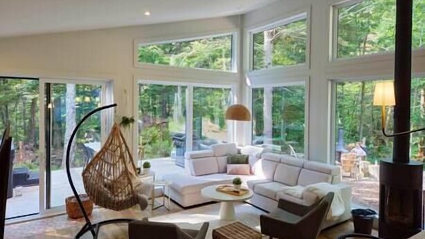 A spacious living room with a large window, a hanging chair, and a fireplace. - EARTH chalet in harmony with nature, Tremblant (Mont-Tremblant)