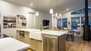 A modern kitchen with a central island, pendant lighting, and a large window. - EARTH chalet in harmony with nature, Tremblant (Mont-Tremblant)