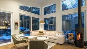 A modern living room with a large sectional sofa, a round coffee table, and a fireplace. - EARTH chalet in harmony with nature, Tremblant (Mont-Tremblant)