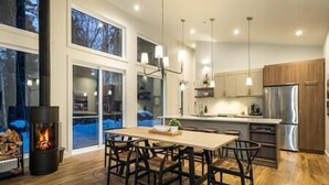 A modern kitchen with a large island, stainless steel appliances, and a fireplace. - EARTH chalet in harmony with nature, Tremblant (Mont-Tremblant)