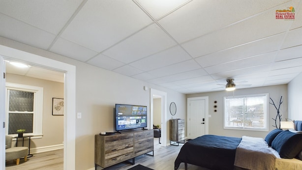 Une chambre à coucher moderne avec un lit, une télévision, une commode et une fenêtre.