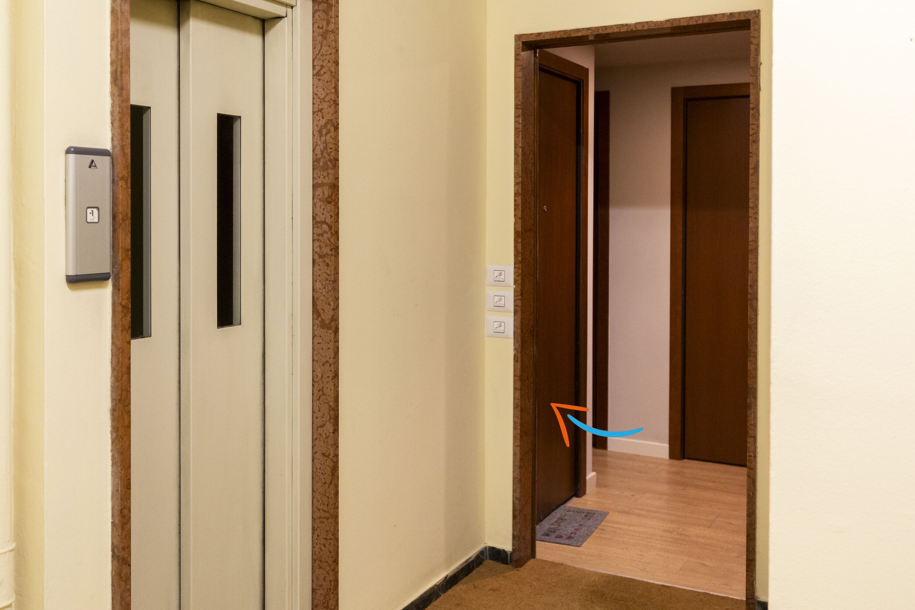A hallway with a door on the left, a light switch, and a door on the right.
