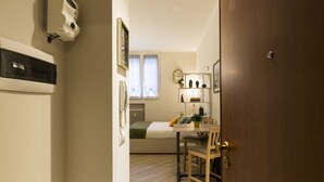 A compact room with a bed, bedside table, and a small desk with a chair. - notaMi - City Charme Studio (Milan)
