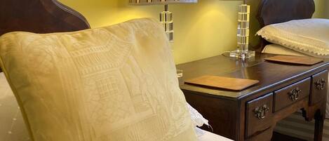 A hotel room with a bed, a nightstand with two lamps, a wooden headboard, and a decorative pillow.