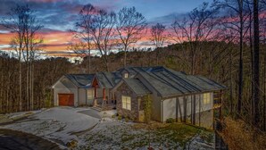 Et toetagers hus med stenvægge, garage og overdækket veranda.