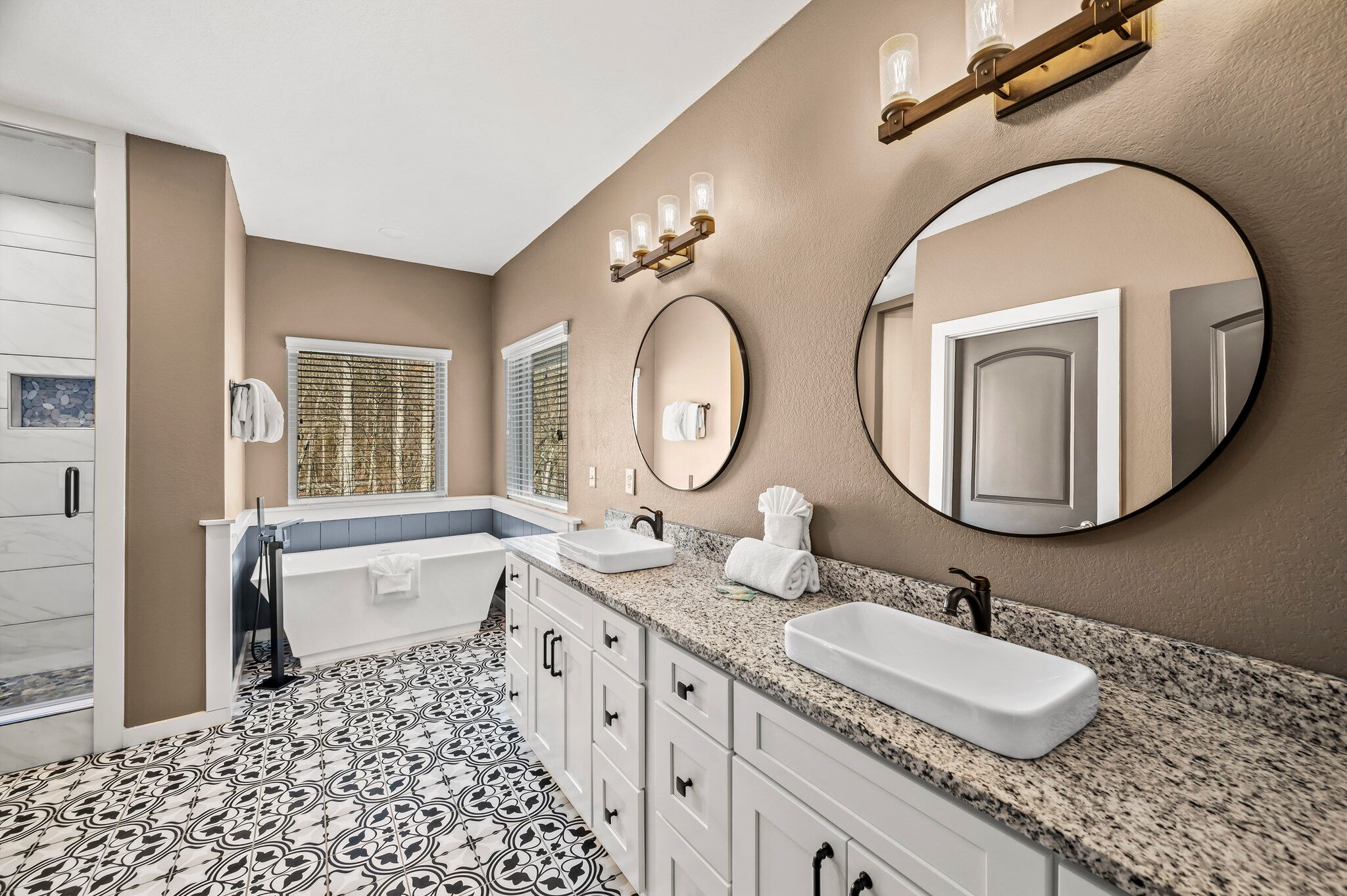 A modern bathroom with a large vanity, two sinks, a bathtub, and a large mirror.