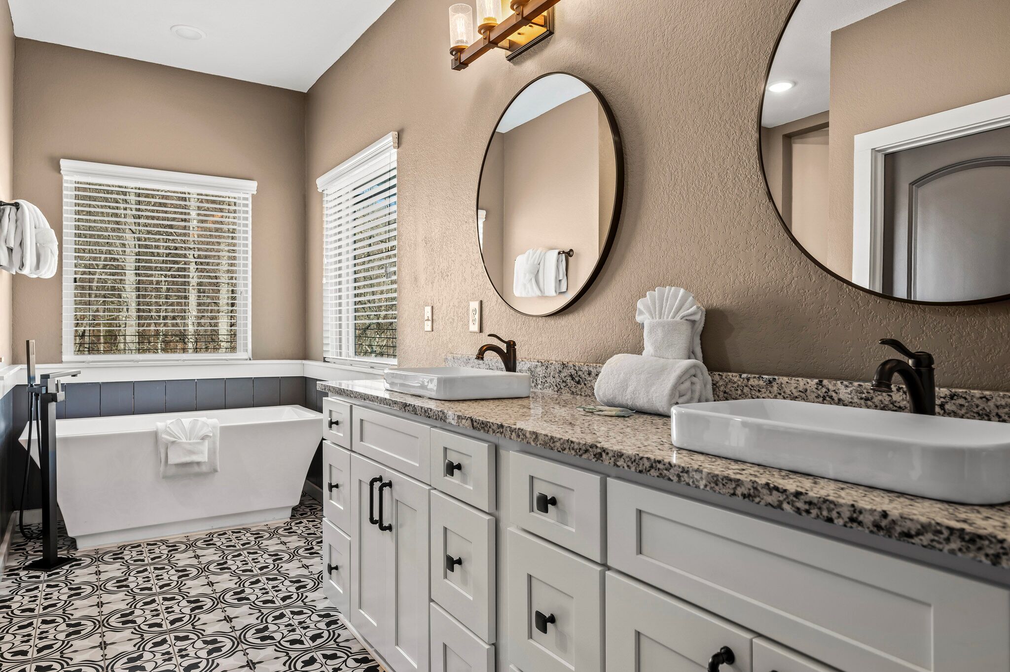 A modern bathroom with a bathtub, two sinks, and a large mirror.