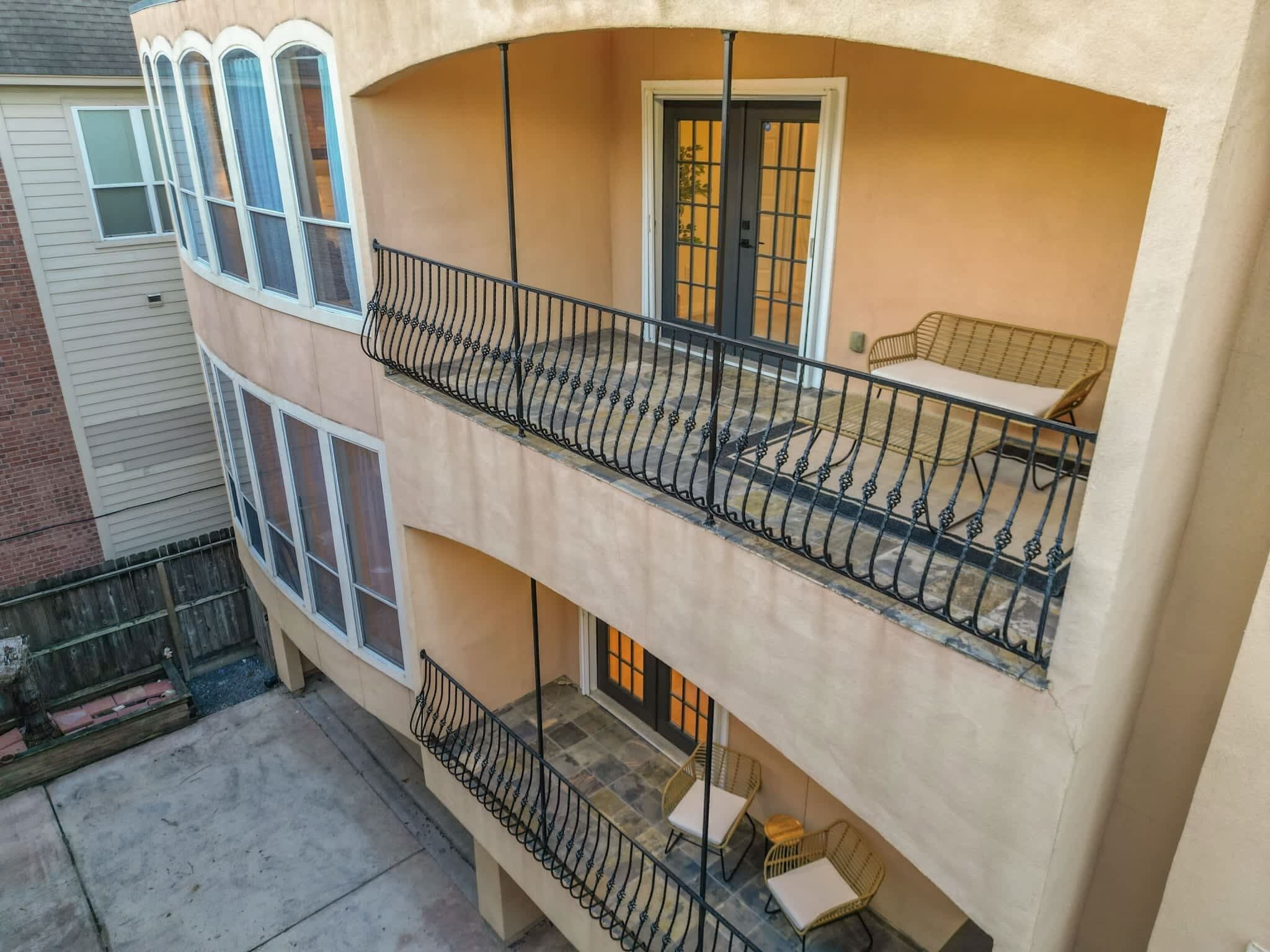 Un immeuble de deux étages doté d’un balcon à l’étage supérieur, et comprenant un petit espace extérieur aménagé avec des meubles en osier.