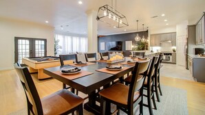 A modern kitchen with a central island, a dining area with a large table and chairs, and a living area with a sofa and TV. - Best of Midtown-3 Bedrooms, Minutes to Attractions (Houston)