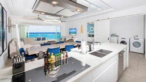 Uma cozinha moderna com uma ilha central, eletrodomésticos embutidos e vista para o oceano.