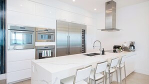 Uma cozinha moderna com eletrodomésticos de aço inoxidável, uma ilha de mármore e banquetas.