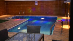 Piscina interior com paredes azulejadas e placa proibindo saltos.