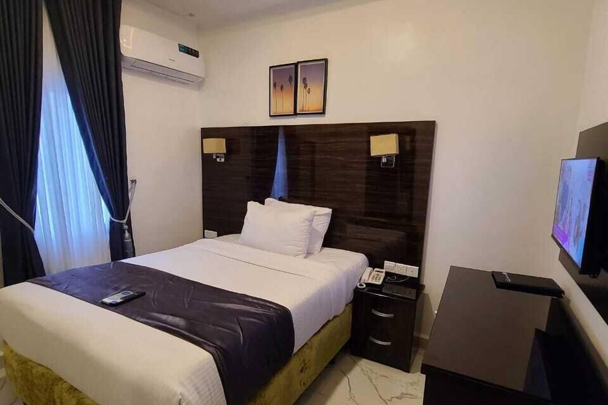 Une chambre d’hôtel moderne, dotée d’un grand lit, d’un bureau et d’une télévision.