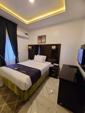 A modern hotel room with a large bed, a desk, and a television. - Mapleviewhotels and Suite Limited (Lekki)