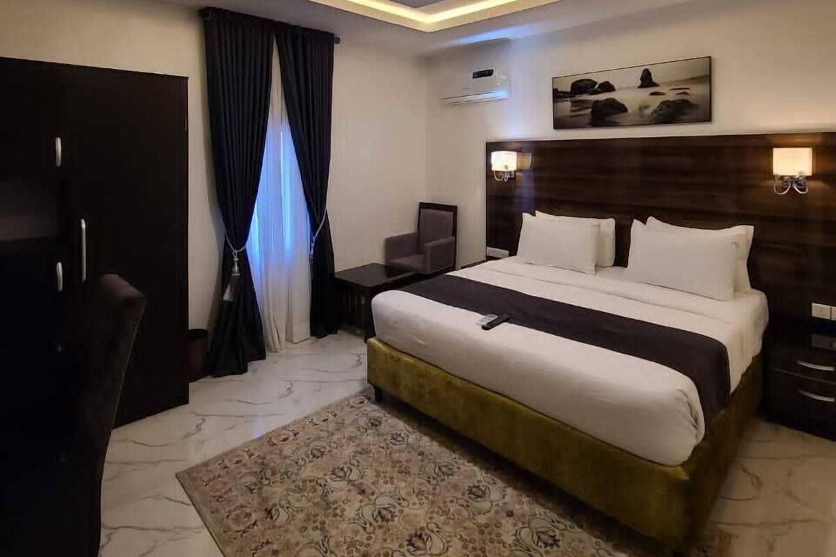 Une chambre d’hôtel moderne équipée d’un grand lit, d’un bureau, d’une chaise et d’un luminaire au plafond.