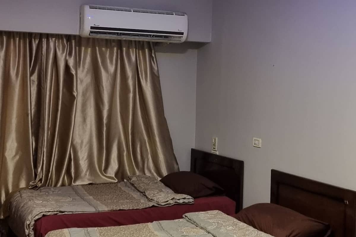A hotel room with two beds, an air conditioning unit, and a ceiling with circular lighting.
