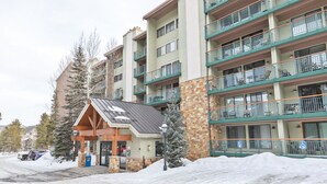 A multi-story hotel with balconies, a stone facade, and a covered entrance. - Trails End Mountainside Condo: Ski-In/Out, Downtown Breck (Breckenridge)