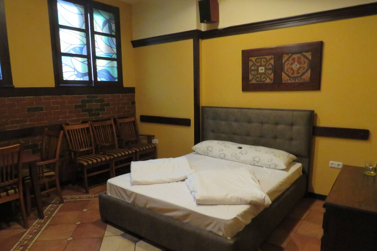 Un dormitorio con una cama, sillas, un ventanal y una pared con un diseño decorativo.