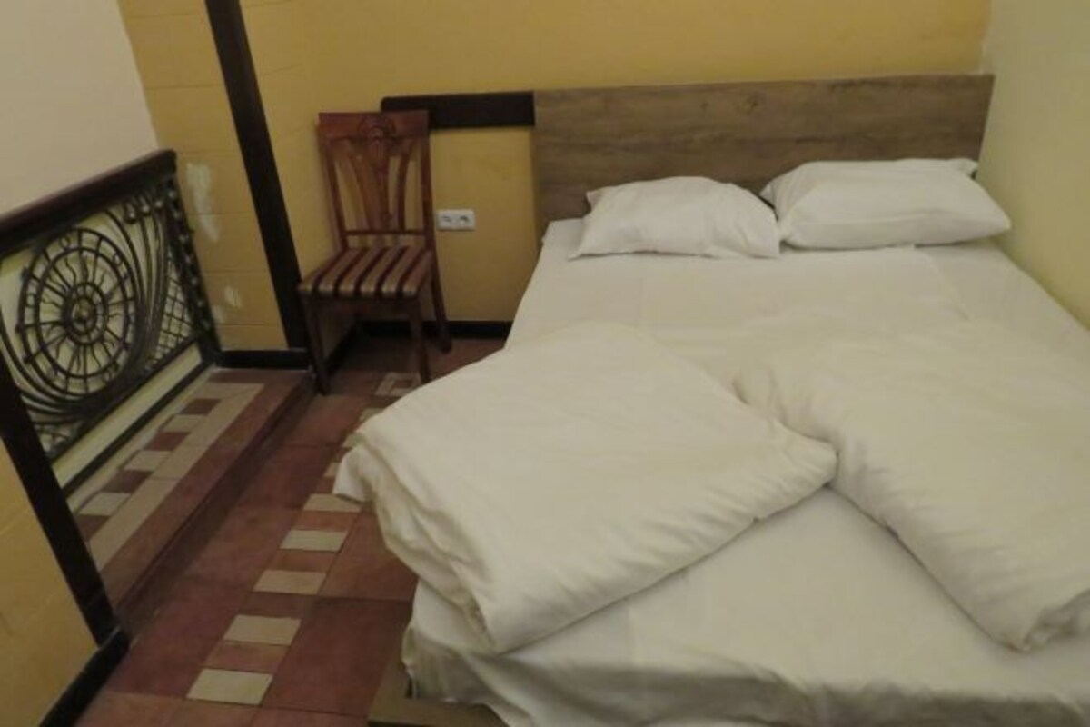 A single bed with white bedding in a room with yellow walls and a wooden headboard.
