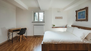 Ein Schlafzimmer mit einem hölzernen Bett, einem Schreibtisch, einem Stuhl, einer Heizung und einem Fenster.