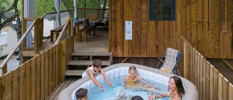 Una cabaña de madera con un jacuzzi rodeado por una terraza de madera.