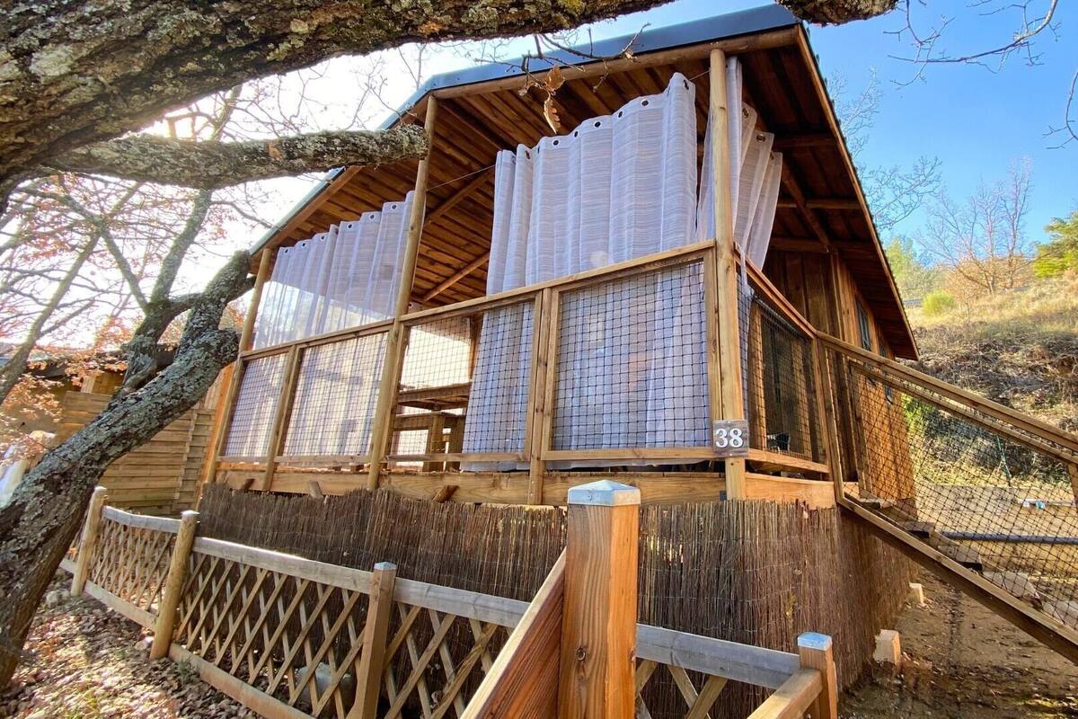 Una estructura de madera con porche cubierto y zona cercada.