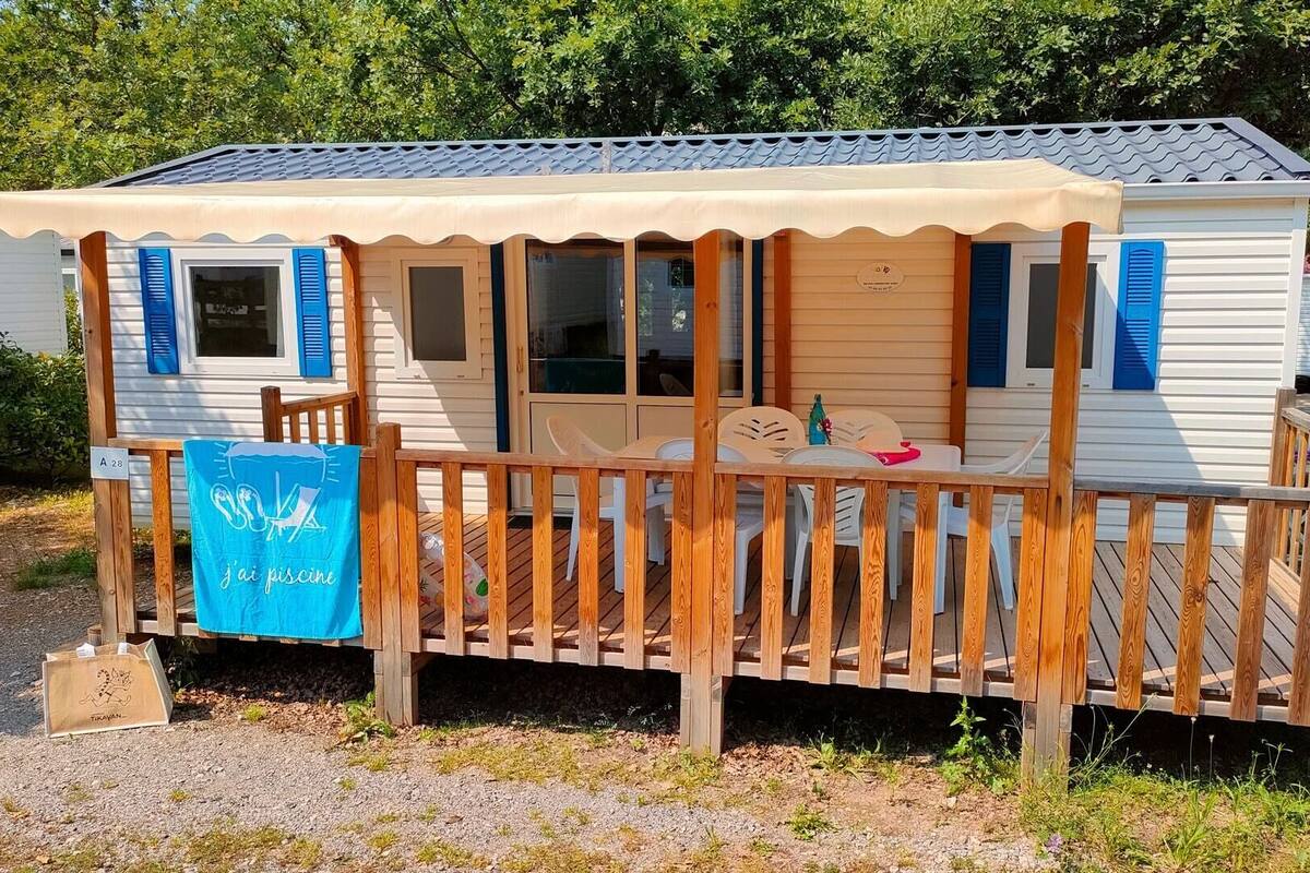 Una casa móvil con terraza, una mesita y sillas.