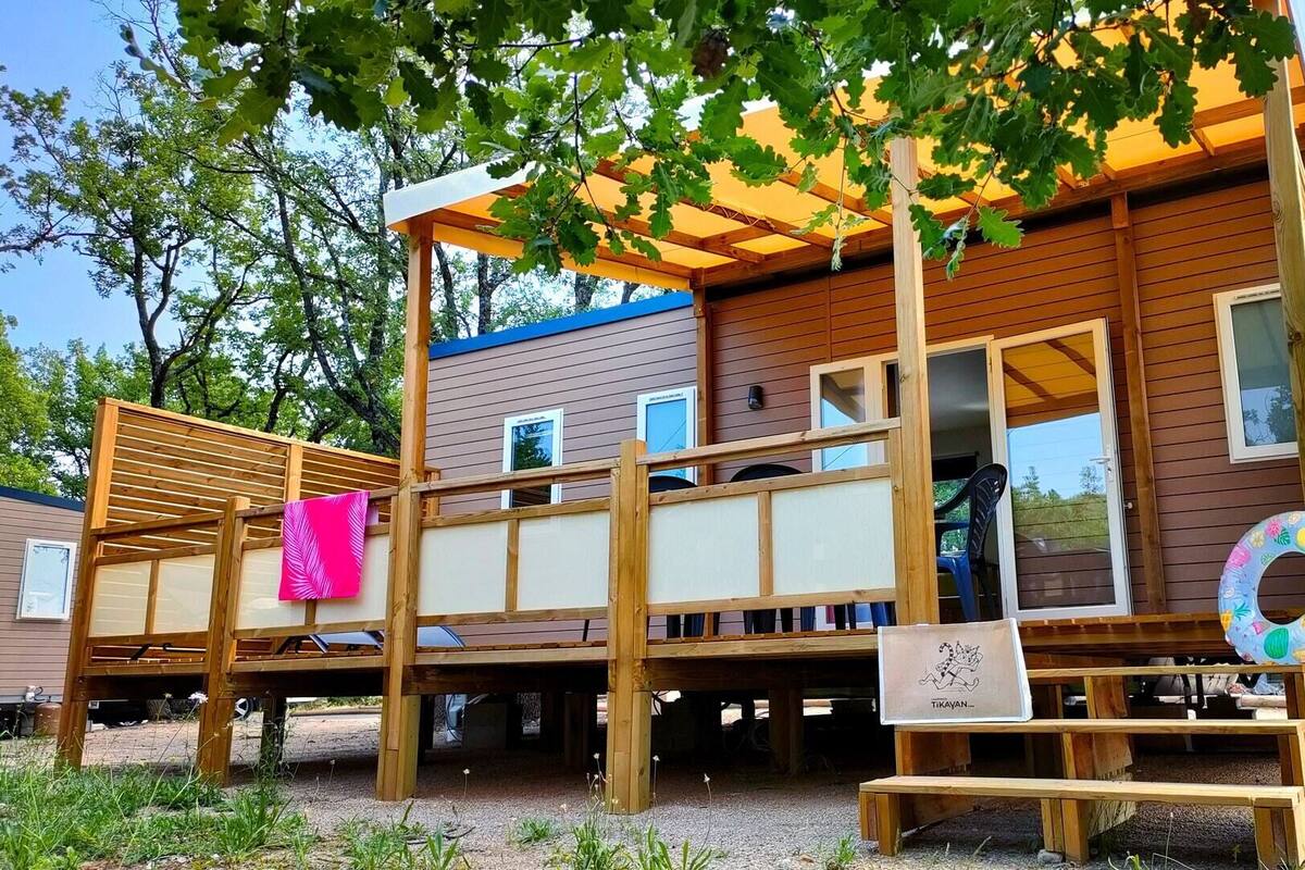 Una terraza de madera con pérgola, un banco y un anillo flotante.