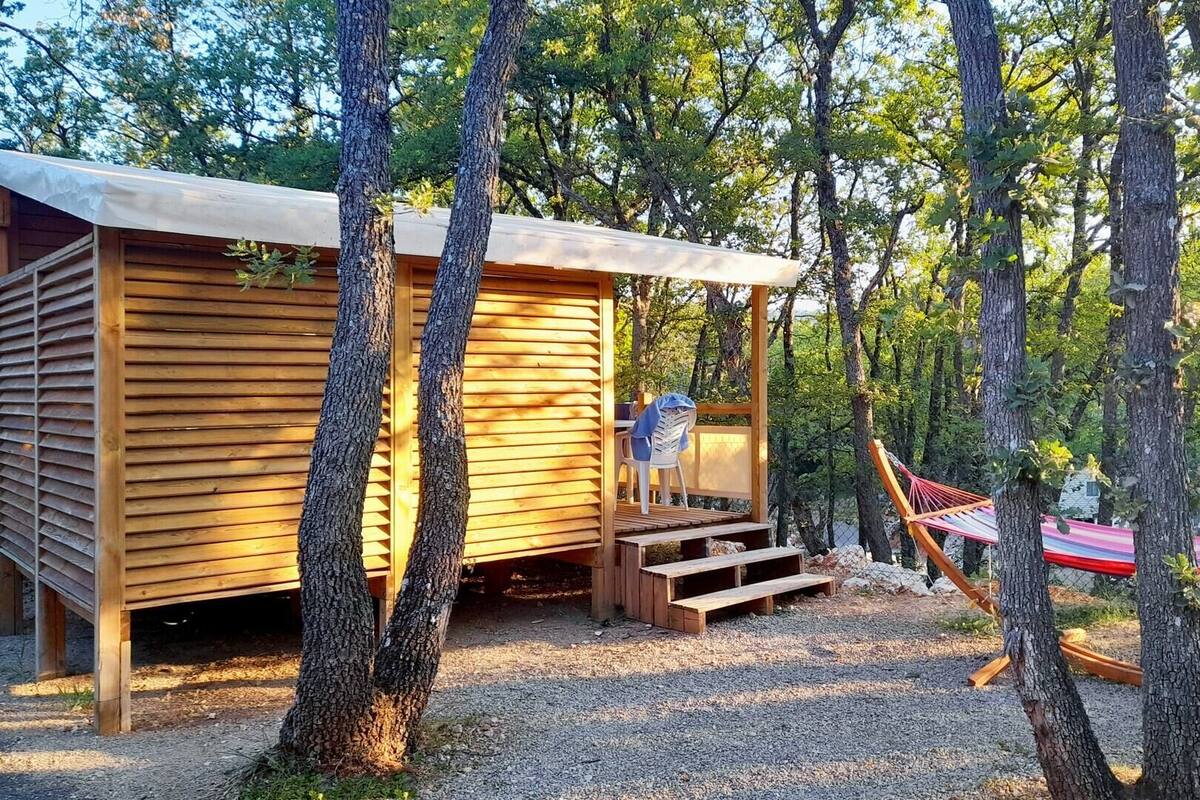 Una cabaña de madera con un porche cubierto, una hamaca y una silla.