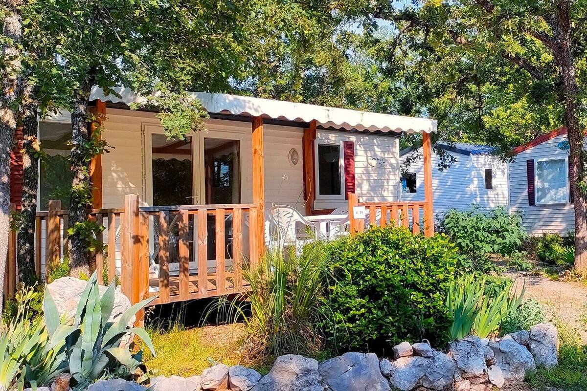 Una casa móvil con porche y un pequeño jardín.