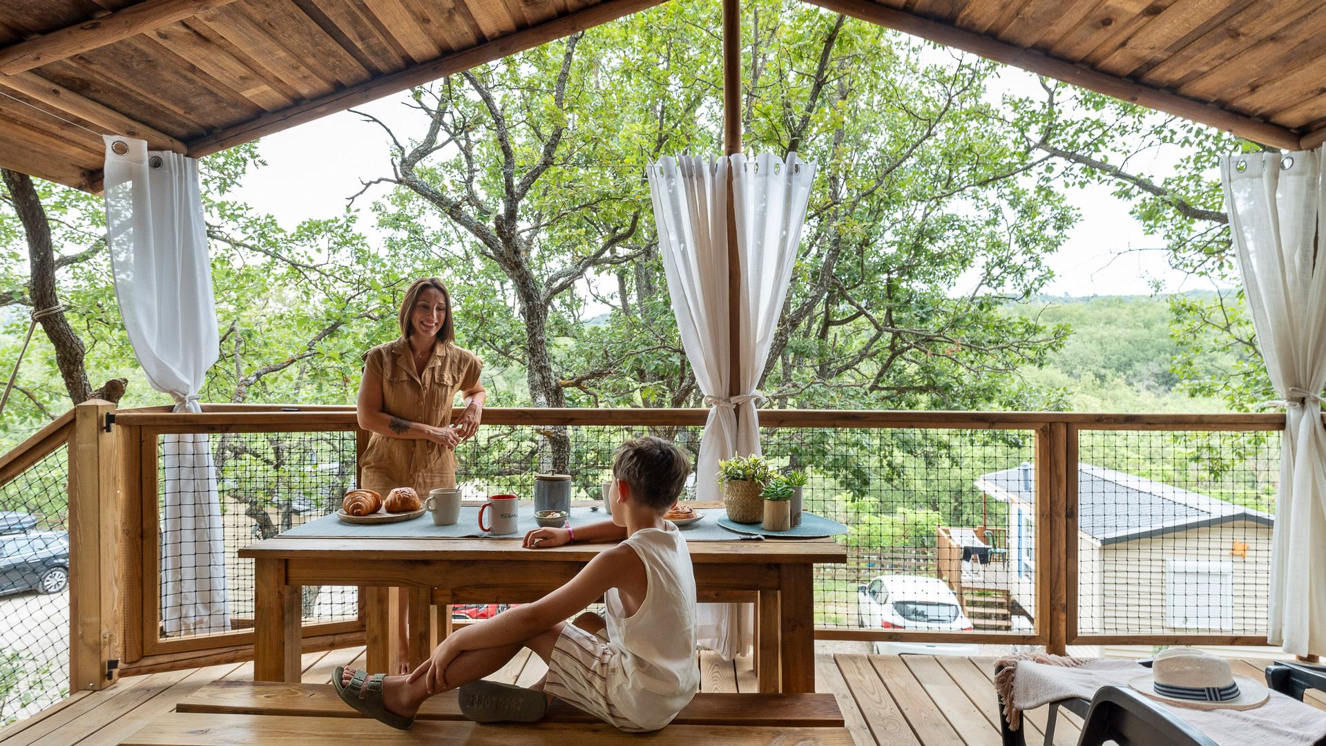 Een houten terras met een ontbijttafel, met uitzicht op een groen landschap.